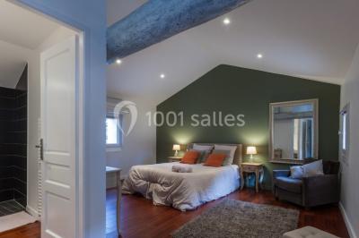 Tente en toile beige installée sur un sol gravillonné, entourée d'arbres, avec des lits aménagés à l'intérieur.