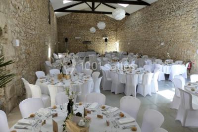 Tente en toile beige installée sur un sol gravillonné, entourée d'arbres, avec des lits aménagés à l'intérieur.