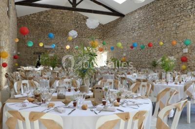Tente en toile beige installée sur un sol gravillonné, entourée d'arbres, avec des lits aménagés à l'intérieur.