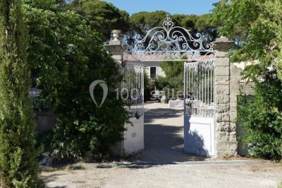 Tente en toile beige installée sur un sol gravillonné, entourée d'arbres, avec des lits aménagés à l'intérieur.