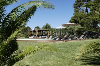 Tente en toile beige installée sur un sol gravillonné, entourée d'arbres, avec des lits aménagés à l'intérieur.