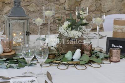 Tente en toile beige installée sur un sol gravillonné, entourée d'arbres, avec des lits aménagés à l'intérieur.