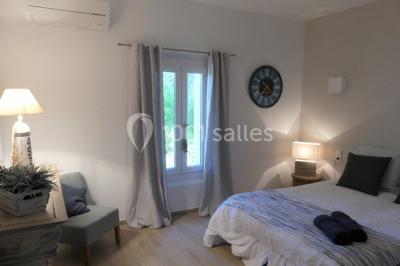 Tente en toile beige installée sur un sol gravillonné, entourée d'arbres, avec des lits aménagés à l'intérieur.