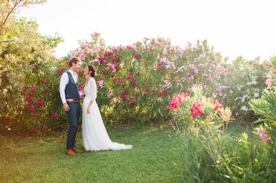 Tente en toile beige installée sur un sol gravillonné, entourée d'arbres, avec des lits aménagés à l'intérieur.