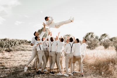 Tente en toile beige installée sur un sol gravillonné, entourée d'arbres, avec des lits aménagés à l'intérieur.