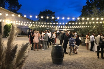 Tente en toile beige installée sur un sol gravillonné, entourée d'arbres, avec des lits aménagés à l'intérieur.