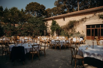Tente en toile beige installée sur un sol gravillonné, entourée d'arbres, avec des lits aménagés à l'intérieur.