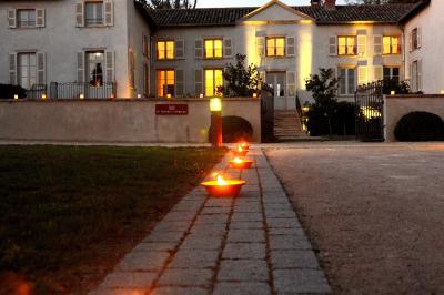 Allée pavée bordée de bougies allumées menant à une grande maison éclairée au crépuscule.
