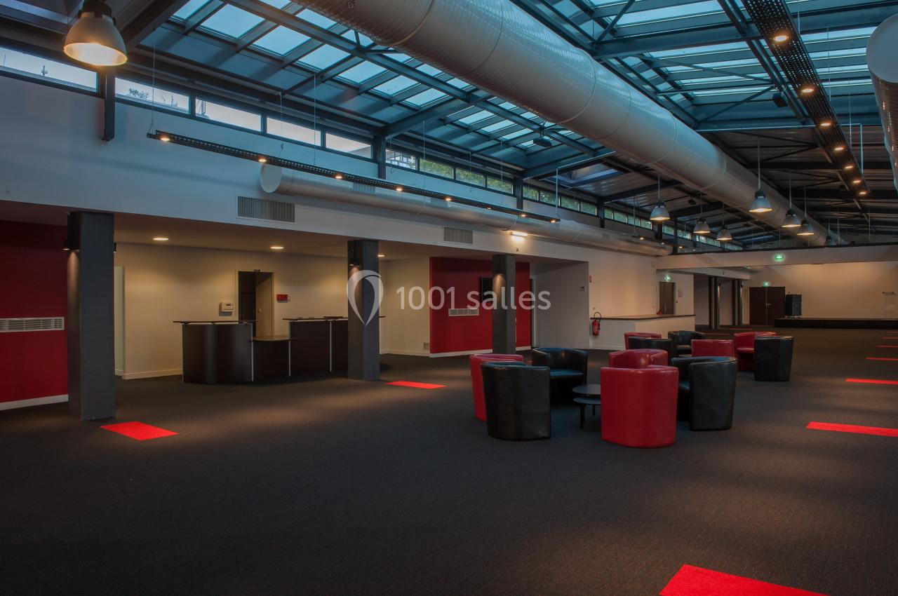 Espace intérieur moderne avec plafond vitré, mobilier rouge et noir, et éclairage tamisé.