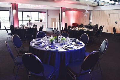 Vue nocturne d'une terrasse éclairée en bleu avec une rivière et un pont illuminé en arrière-plan.