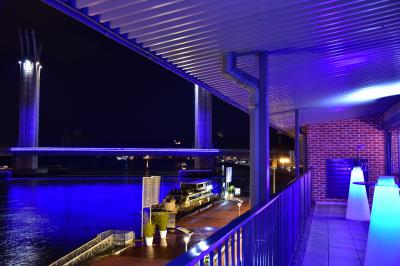 Vue nocturne d'une terrasse éclairée en bleu avec une rivière et un pont illuminé en arrière-plan.