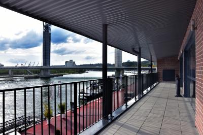 Vue nocturne d'une terrasse éclairée en bleu avec une rivière et un pont illuminé en arrière-plan.