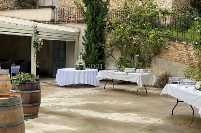 Tables rondes dressées avec nappes blanches et décorations, disposées en extérieur sur une terrasse ensoleillée.