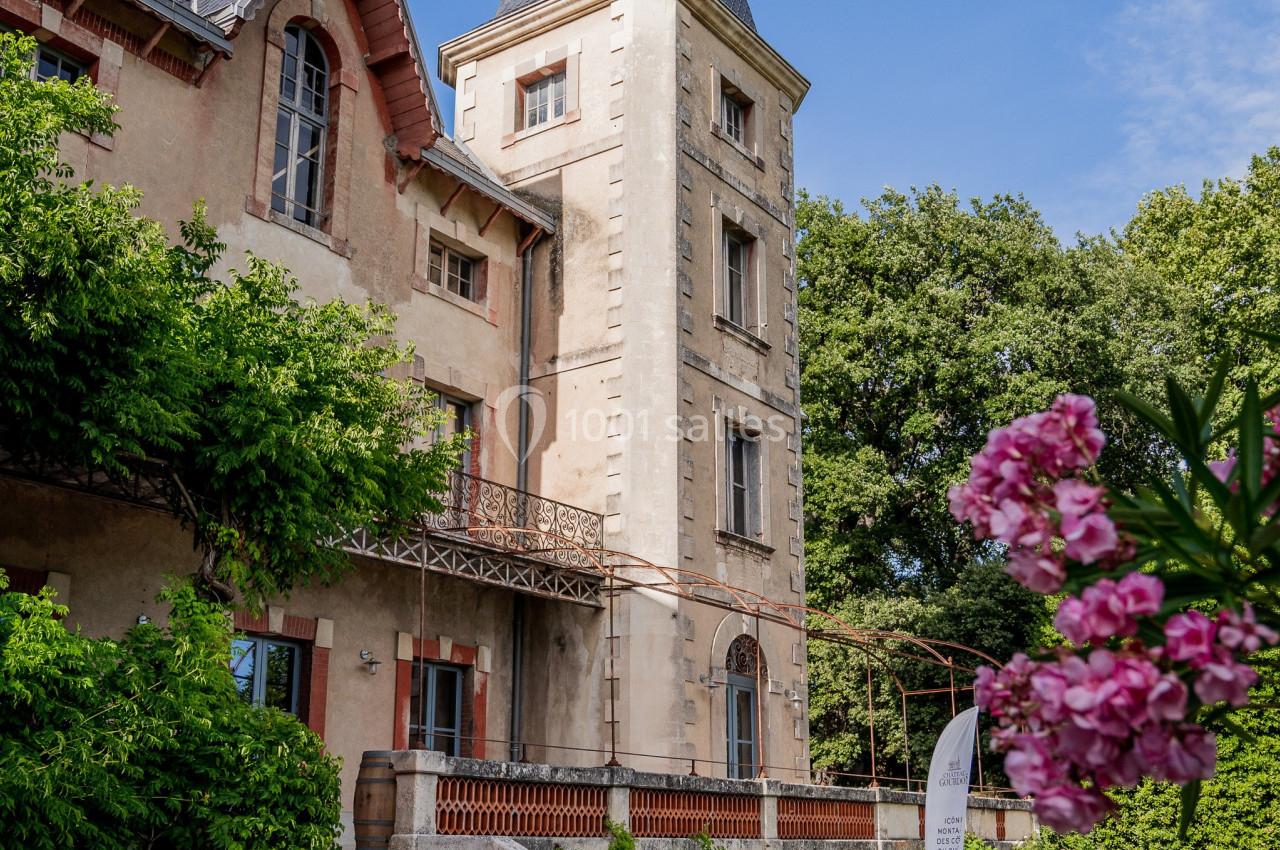 Château avec tour en pierre, tapis rouge à l'entrée, tonneaux en décoration et fleurs au premier plan.