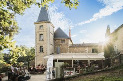 Tables rondes dressées avec nappes blanches et décorations, disposées en extérieur sur une terrasse ensoleillée.