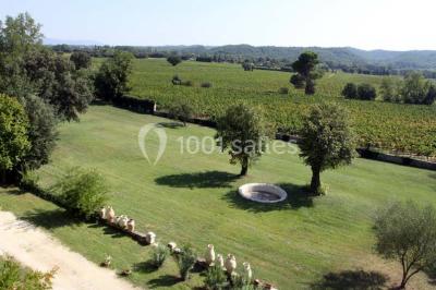 Tables rondes dressées avec nappes blanches et décorations, disposées en extérieur sur une terrasse ensoleillée.