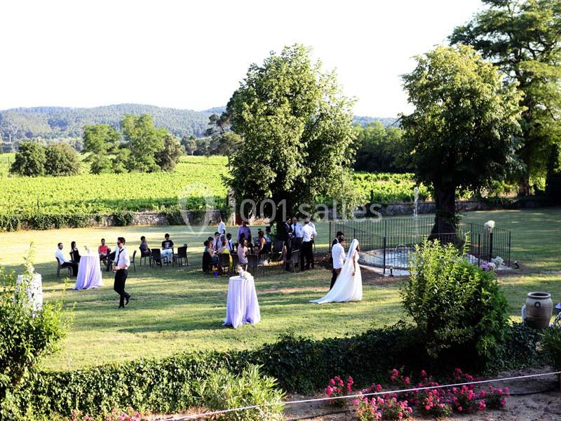 Mariage en plein air dans un jardin verdoyant avec des invités rassemblés près de tables et d'une fontaine.