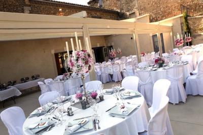 Tables rondes dressées avec nappes blanches et décorations, disposées en extérieur sur une terrasse ensoleillée.