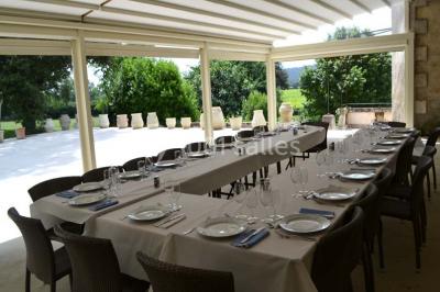 Tables rondes dressées avec nappes blanches et décorations, disposées en extérieur sur une terrasse ensoleillée.