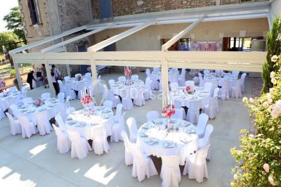 Tables rondes dressées avec nappes blanches et décorations, disposées en extérieur sur une terrasse ensoleillée.