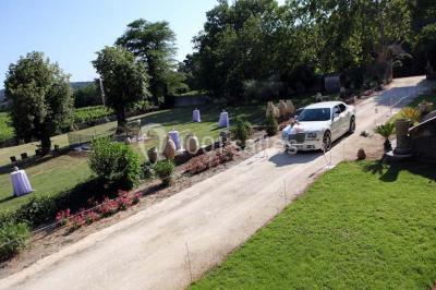 Tables rondes dressées avec nappes blanches et décorations, disposées en extérieur sur une terrasse ensoleillée.