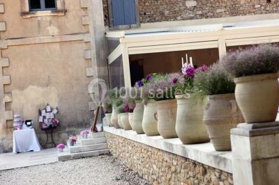 Tables rondes dressées avec nappes blanches et décorations, disposées en extérieur sur une terrasse ensoleillée.