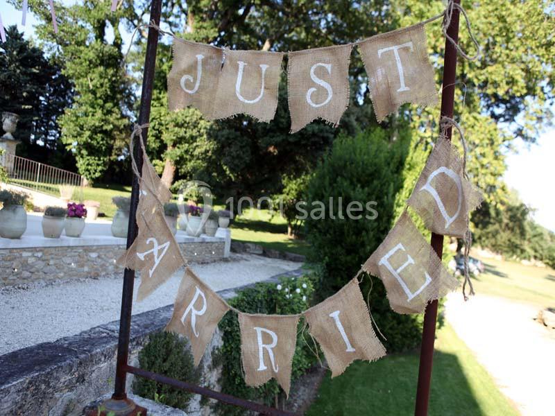 Guirlande en toile de jute avec l'inscription ’Just Married’, accrochée dans un jardin verdoyant.