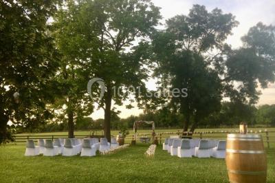 Un couple en tenue de mariage pose devant un groupe de cavaliers alignés sur des chevaux dans un espace verdoyant.