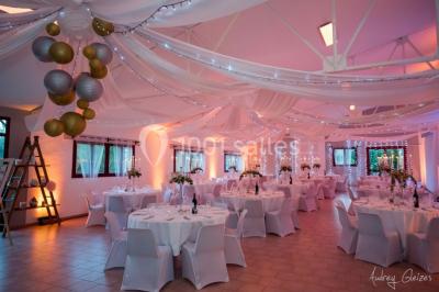 Un couple en tenue de mariage pose devant un groupe de cavaliers alignés sur des chevaux dans un espace verdoyant.