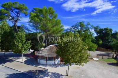 Un couple en tenue de mariage pose devant un groupe de cavaliers alignés sur des chevaux dans un espace verdoyant.