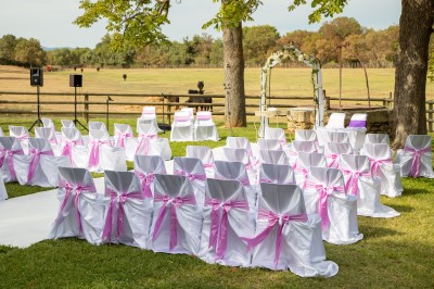 Un couple en tenue de mariage pose devant un groupe de cavaliers alignés sur des chevaux dans un espace verdoyant.