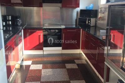 Salle lumineuse avec un grand miroir mural, sol en parquet clair et murs blancs, éclairée par des spots au plafond.