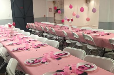 Salle lumineuse avec un grand miroir mural, sol en parquet clair et murs blancs, éclairée par des spots au plafond.