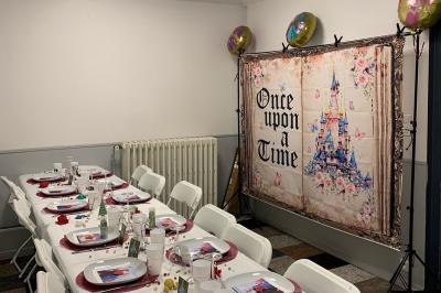 Salle lumineuse avec un grand miroir mural, sol en parquet clair et murs blancs, éclairée par des spots au plafond.