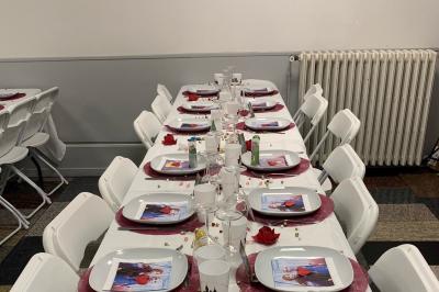 Salle lumineuse avec un grand miroir mural, sol en parquet clair et murs blancs, éclairée par des spots au plafond.