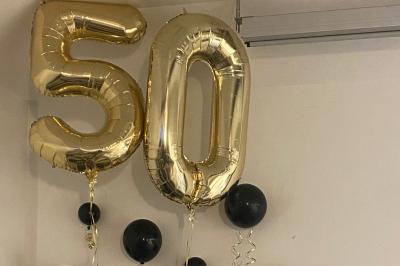 Salle lumineuse avec un grand miroir mural, sol en parquet clair et murs blancs, éclairée par des spots au plafond.