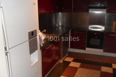 Cuisine moderne avec meubles rouges, plan de travail noir, électroménagers intégrés et carrelage à motifs au sol.