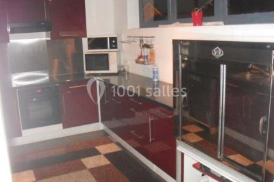 Cuisine moderne avec meubles rouges, plan de travail noir, électroménagers intégrés et carrelage à motifs au sol.