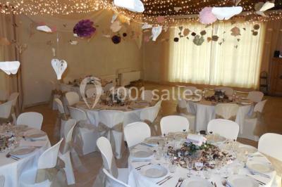 Façade d'une maison provençale avec terrasse ombragée, tables en fer forgé et grand arbre au premier plan.