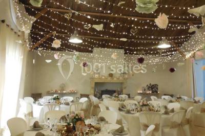 Façade d'une maison provençale avec terrasse ombragée, tables en fer forgé et grand arbre au premier plan.