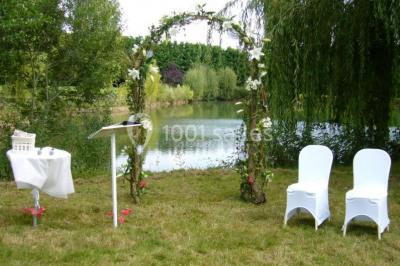 Voiture ancienne bleue décorée de rubans blancs et de fleurs pour une cérémonie, stationnée en extérieur.