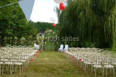 Voiture ancienne bleue décorée de rubans blancs et de fleurs pour une cérémonie, stationnée en extérieur.