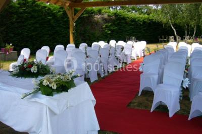 Voiture ancienne bleue décorée de rubans blancs et de fleurs pour une cérémonie, stationnée en extérieur.
