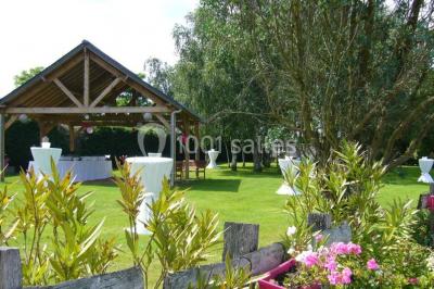 Voiture ancienne bleue décorée de rubans blancs et de fleurs pour une cérémonie, stationnée en extérieur.
