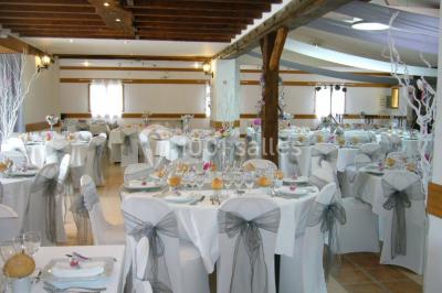 Voiture ancienne bleue décorée de rubans blancs et de fleurs pour une cérémonie, stationnée en extérieur.