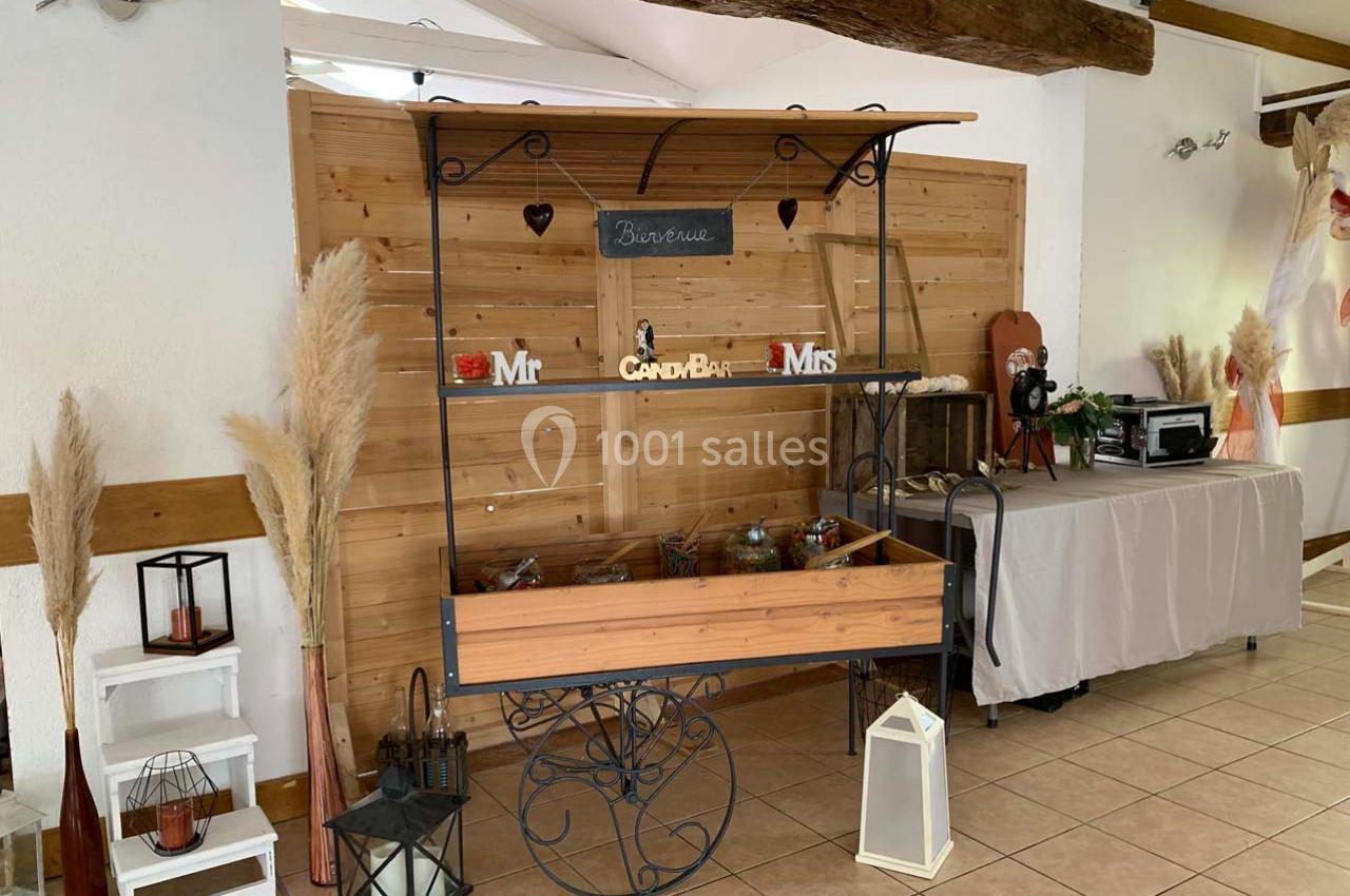 Chariot en bois décoratif avec bonbonnières, placé devant un mur en bois, entouré de lanternes et de décorations.