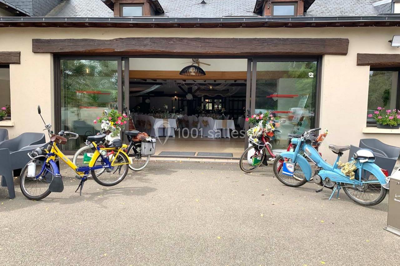 Quatre vélos colorés stationnés devant l'entrée vitrée d'un bâtiment décoré pour un événement.