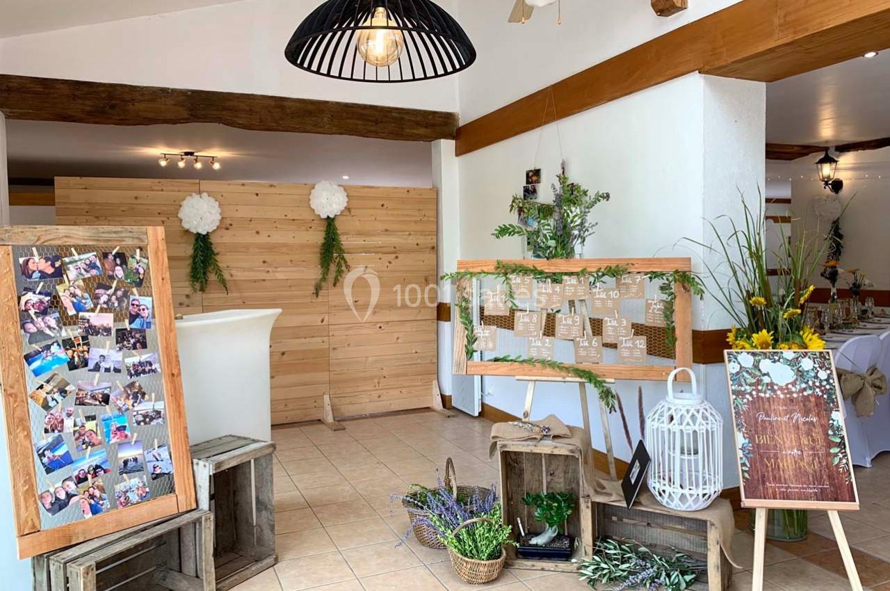 Décoration de salle avec panneaux en bois, photos, fleurs et éléments rustiques pour un événement festif.