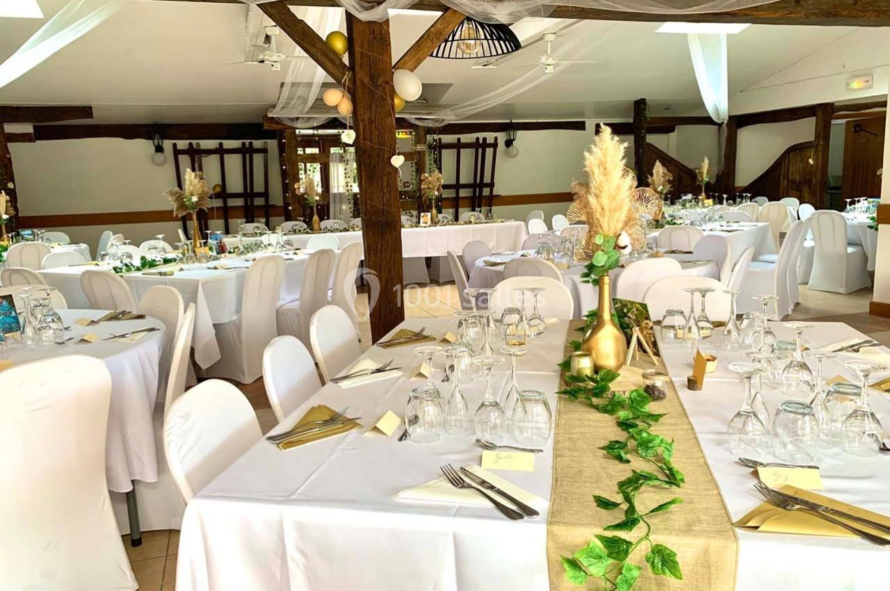 Salle de réception décorée avec des tables dressées, nappes blanches, chemins de table en lin et ornements végétaux.