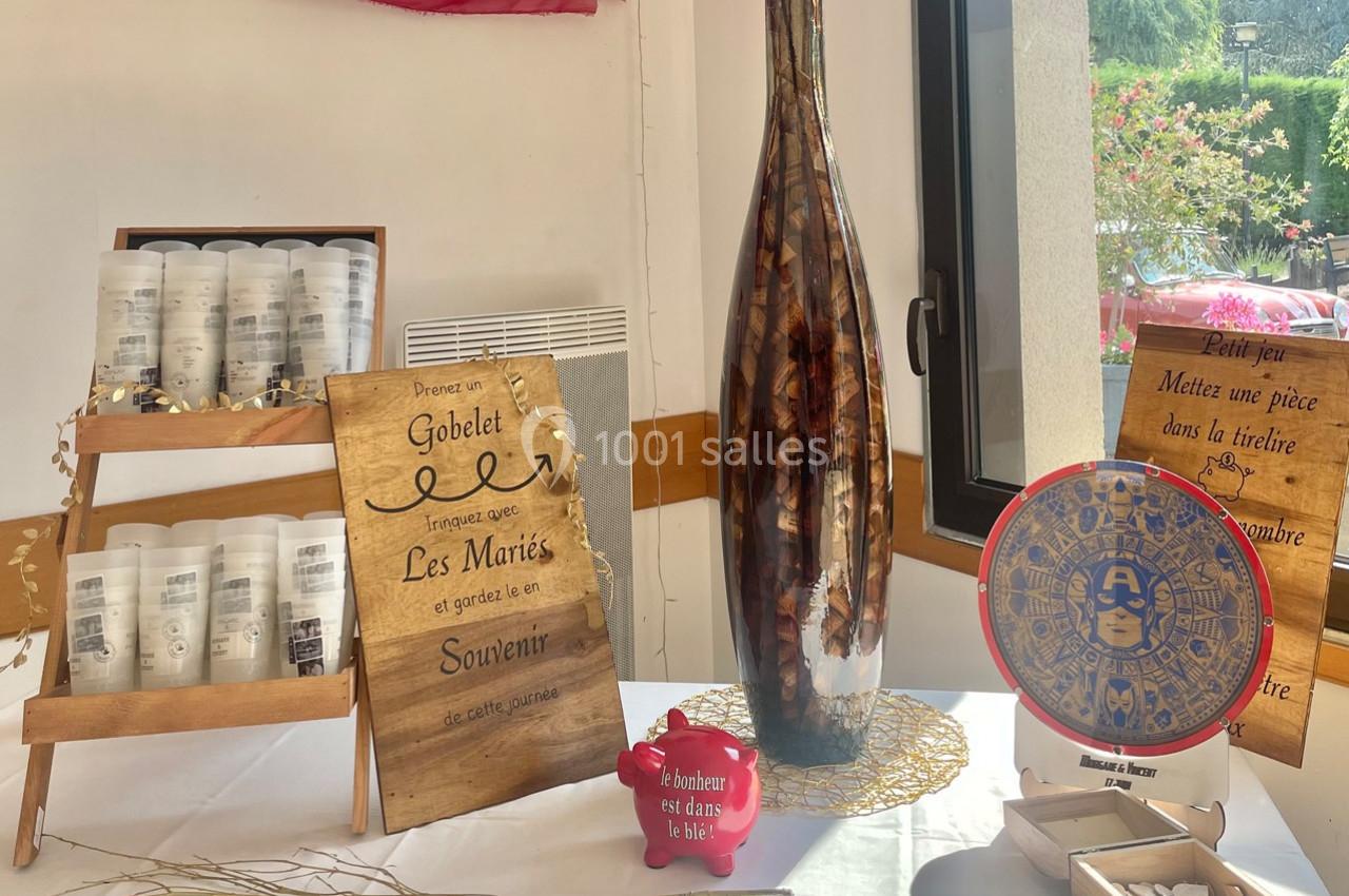 Table décorative avec des souvenirs de mariage, comprenant des gobelets personnalisés, une urne et une roue de jeu.